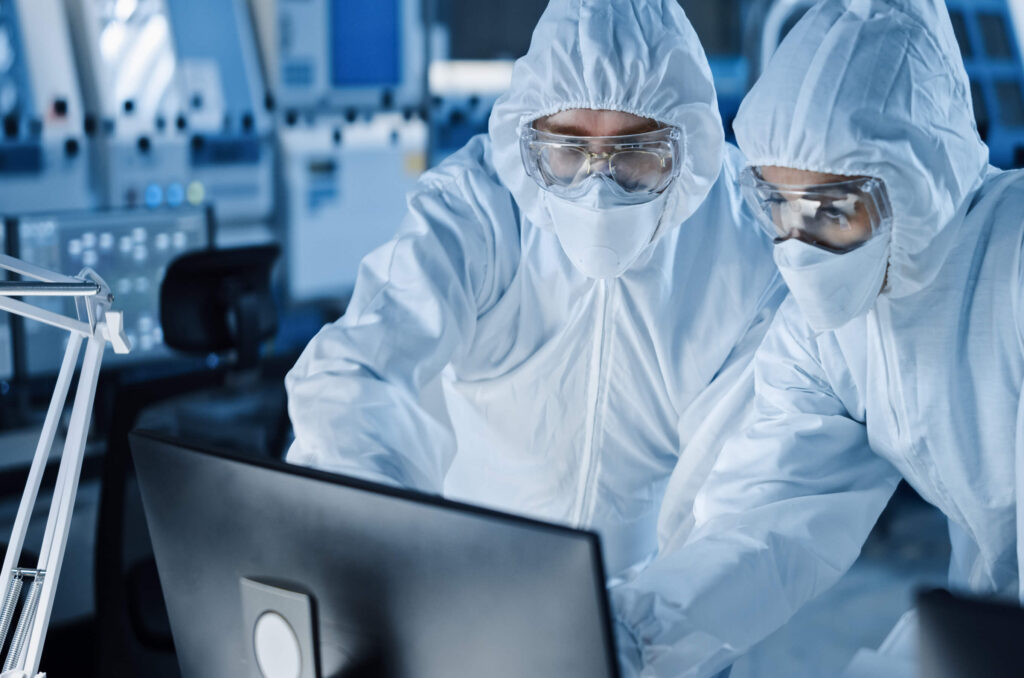 Two people in a clean room collaborating by a computer